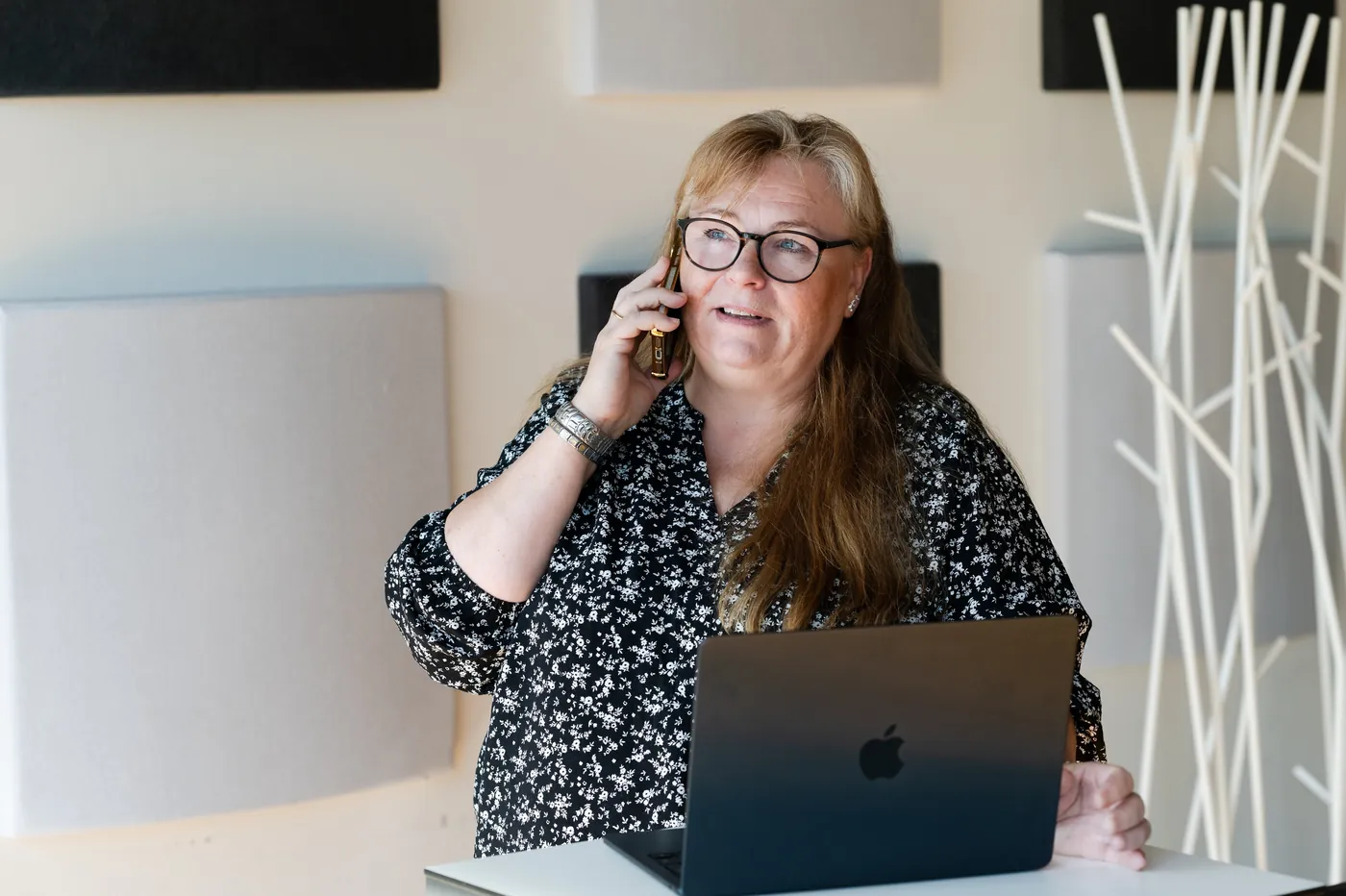 Kiinteistöassistentti Minna Kinnunen puhelimessa kannettavan tietokoneen ääressä